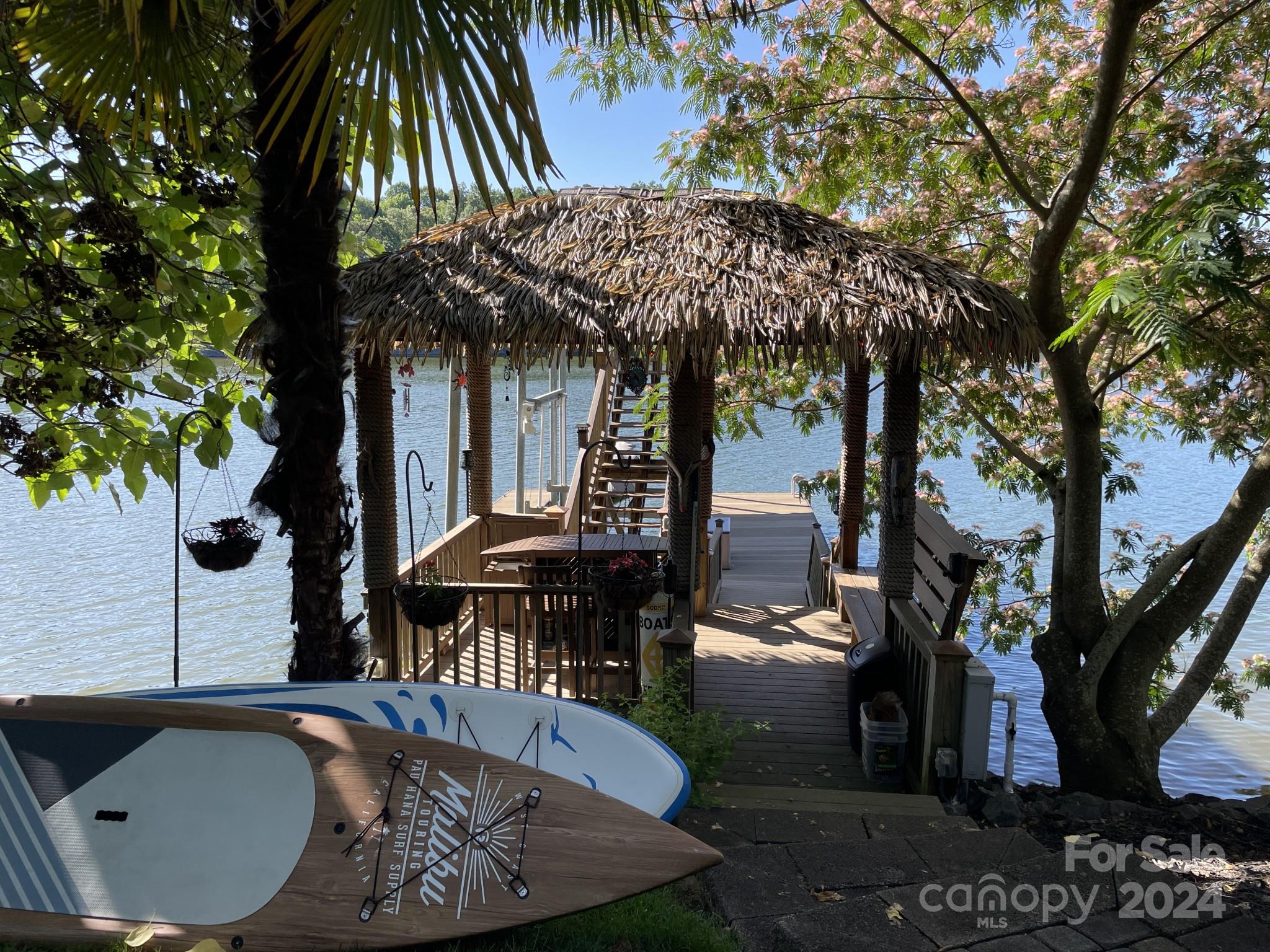 936 Rocky Point Lane Tega Cay, SC 29708 - Photo 21 of 48 a view of a patio with table and chairs under an umbrella with a large tree