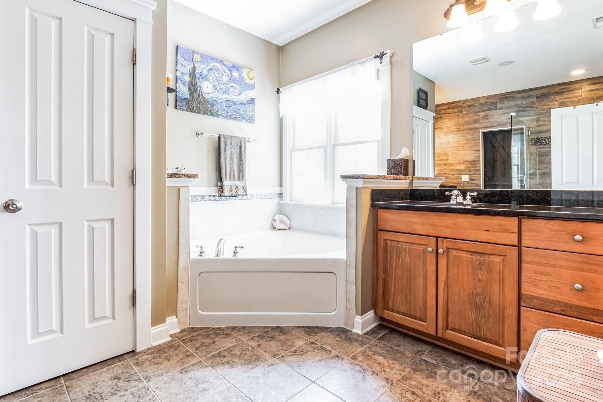 936 Rocky Point Lane Tega Cay, SC 29708 - Photo 32 of 48 a spacious bathroom with a granite countertop sink and a mirror