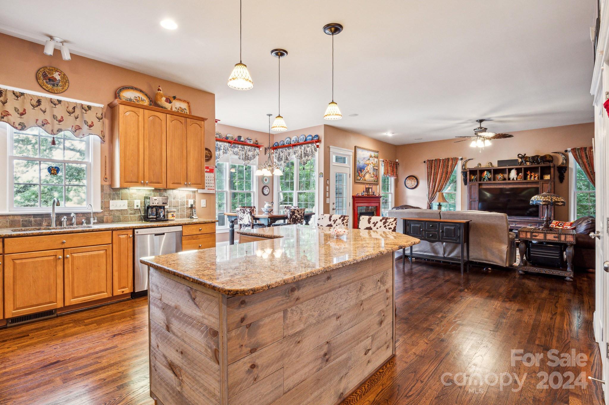 936 Rocky Point Lane Tega Cay, SC 29708 - Photo 45 of 48 a large kitchen with kitchen island granite countertop a stove a sink a dining table and chairs with wooden floor