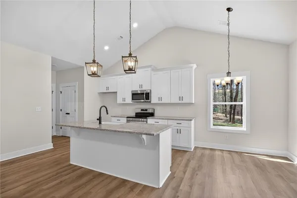 a view of kitchen with stainless steel appliances refrigerator stove and wooden floor