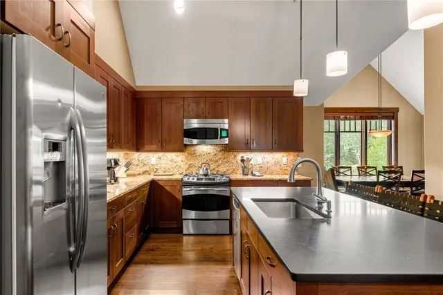 a kitchen with stainless steel appliances granite countertop a sink a stove and a refrigerator