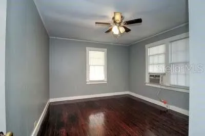 a view of an empty room with wooden floor and a window