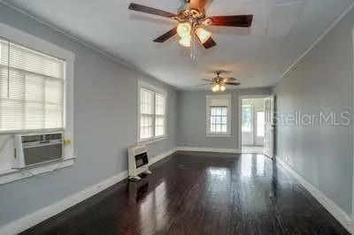 a view of an empty room with wooden floor and a window
