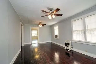 a view of an empty room with a window and wooden floor