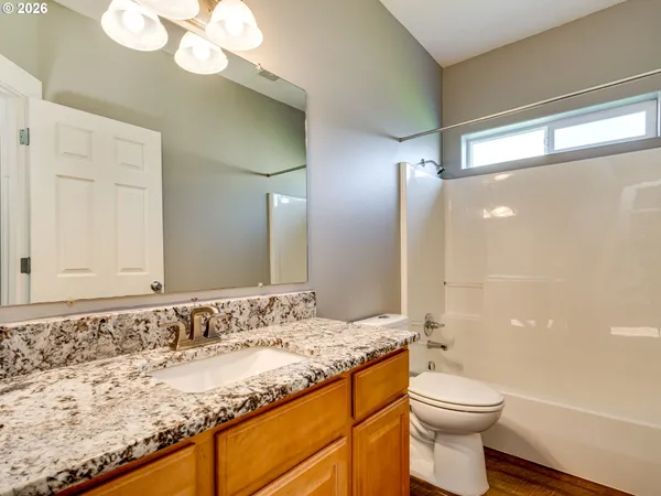 a bathroom with a granite countertop sink a toilet and shower
