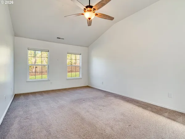 an empty room with windows and chandelier fan