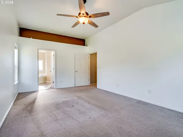 an empty room with a chandelier fan and windows