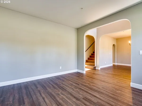 a view of an empty room with wooden floor and a painting