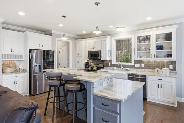 a kitchen with stainless steel appliances granite countertop a stove top oven a sink dishwasher a dining table and chairs with wooden floor