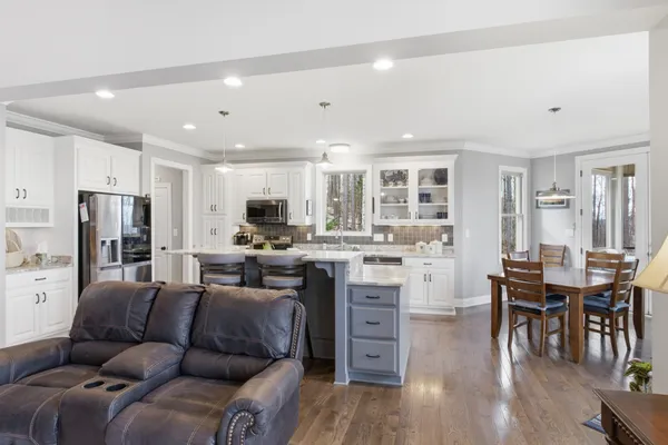 a living room with stainless steel appliances kitchen island granite countertop furniture and wooden floor