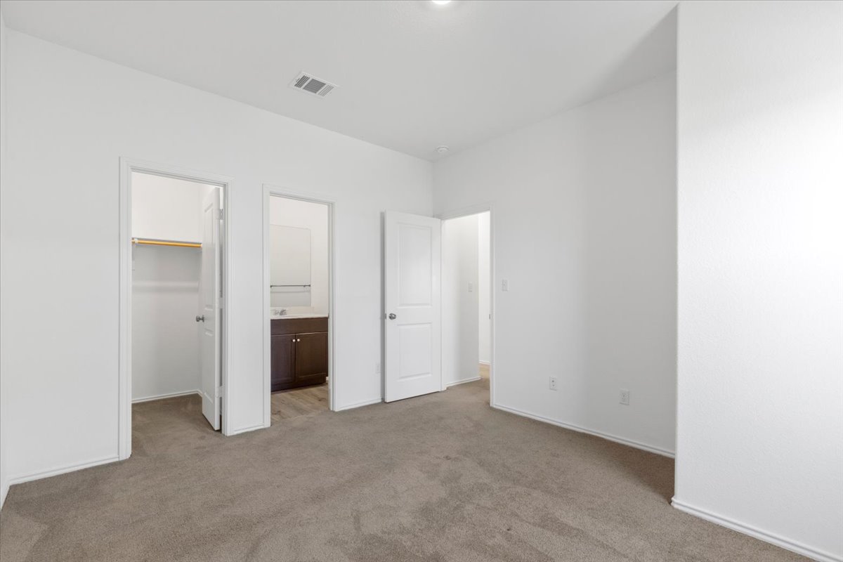 14320 Tordillo Drive Elgin, TX 78621 - Photo 12 of 19 Unfurnished bedroom featuring a spacious closet, ensuite bathroom, and light carpet