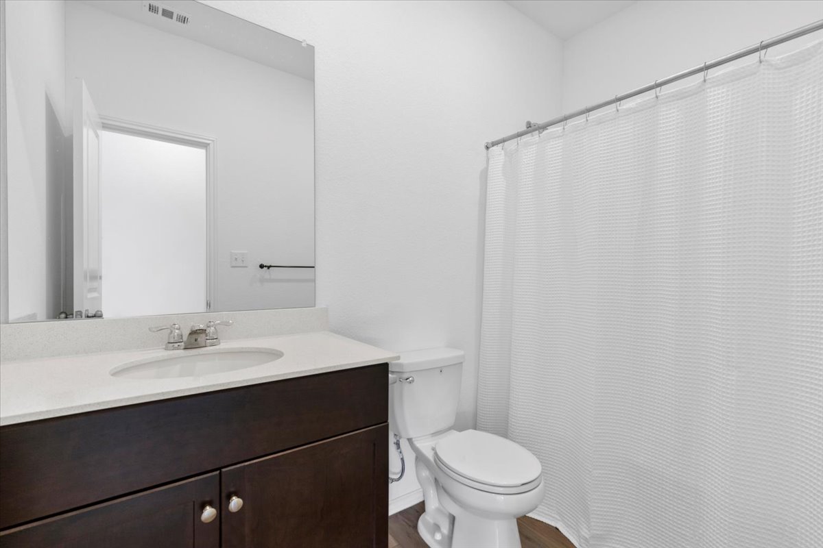 14320 Tordillo Drive Elgin, TX 78621 - Photo 15 of 19 Bathroom featuring a shower with shower curtain, vanity, and dark wood-style flooring