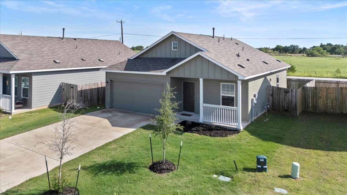 14320 Tordillo Drive Elgin, TX 78621 - Photo 2 of 19 View of front of house featuring roof with shingles, board and batten siding, concrete driveway, a porch, and an attached garage