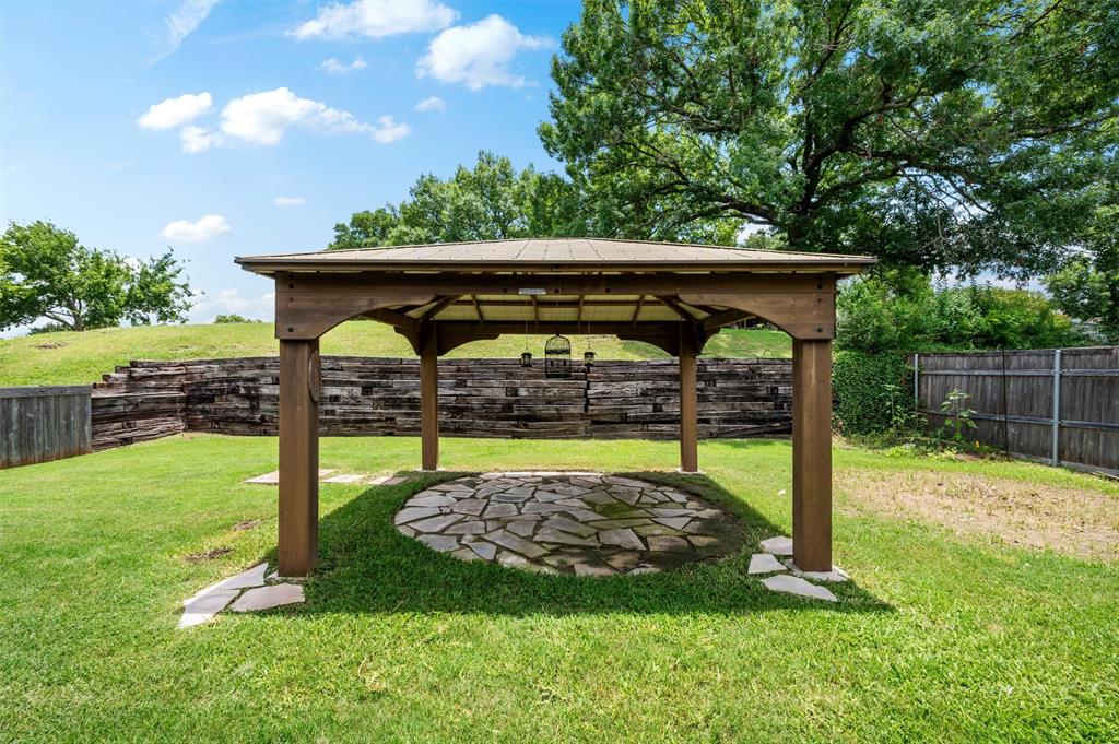 5607 Ranger Drive Rockwall, TX 75032 - Photo 38 of 40 Spacious backyard featuring a wood-frame gazebo with a shingled roof, a flagstone patio, and a terraced retaining wall