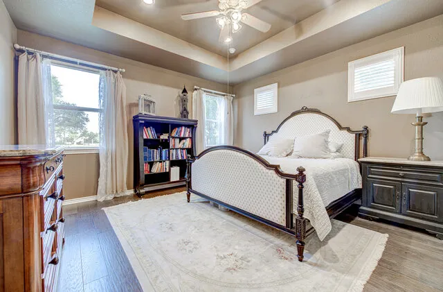 a spacious bedroom with a bed a dresser and a large window