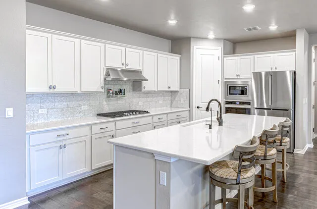 a kitchen with kitchen island granite countertop a sink a center island stainless steel appliances and cabinets