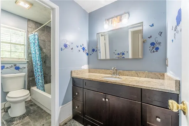a bathroom with a granite countertop sink mirror and toilet