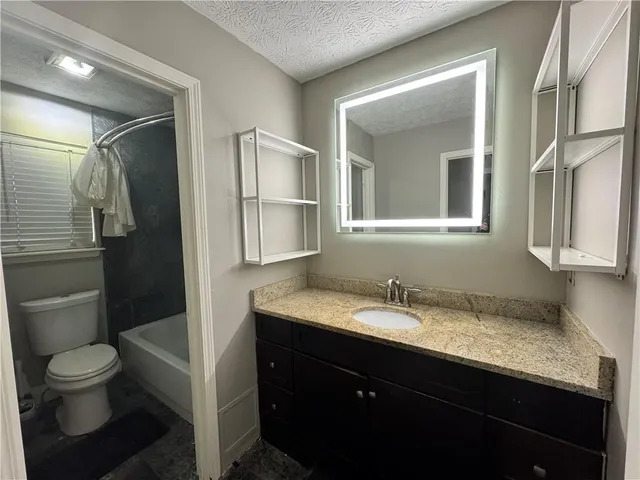 a bathroom with a granite countertop sink toilet and shower