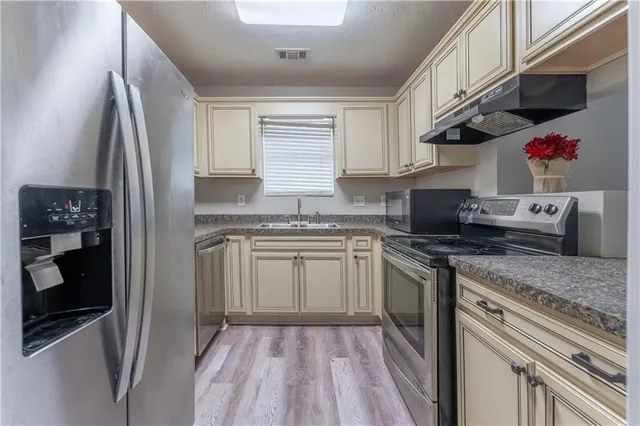 a kitchen with stainless steel appliances granite countertop a stove a sink and a refrigerator