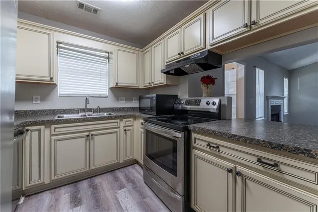 a kitchen with stainless steel appliances granite countertop a sink a stove and cabinets