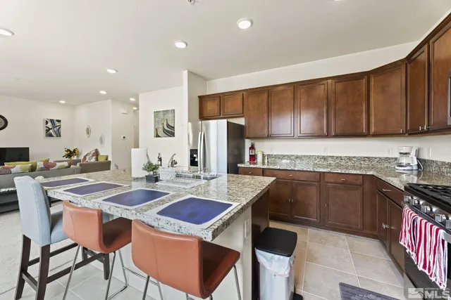 a kitchen with stainless steel appliances granite countertop a table chairs sink refrigerator and cabinets