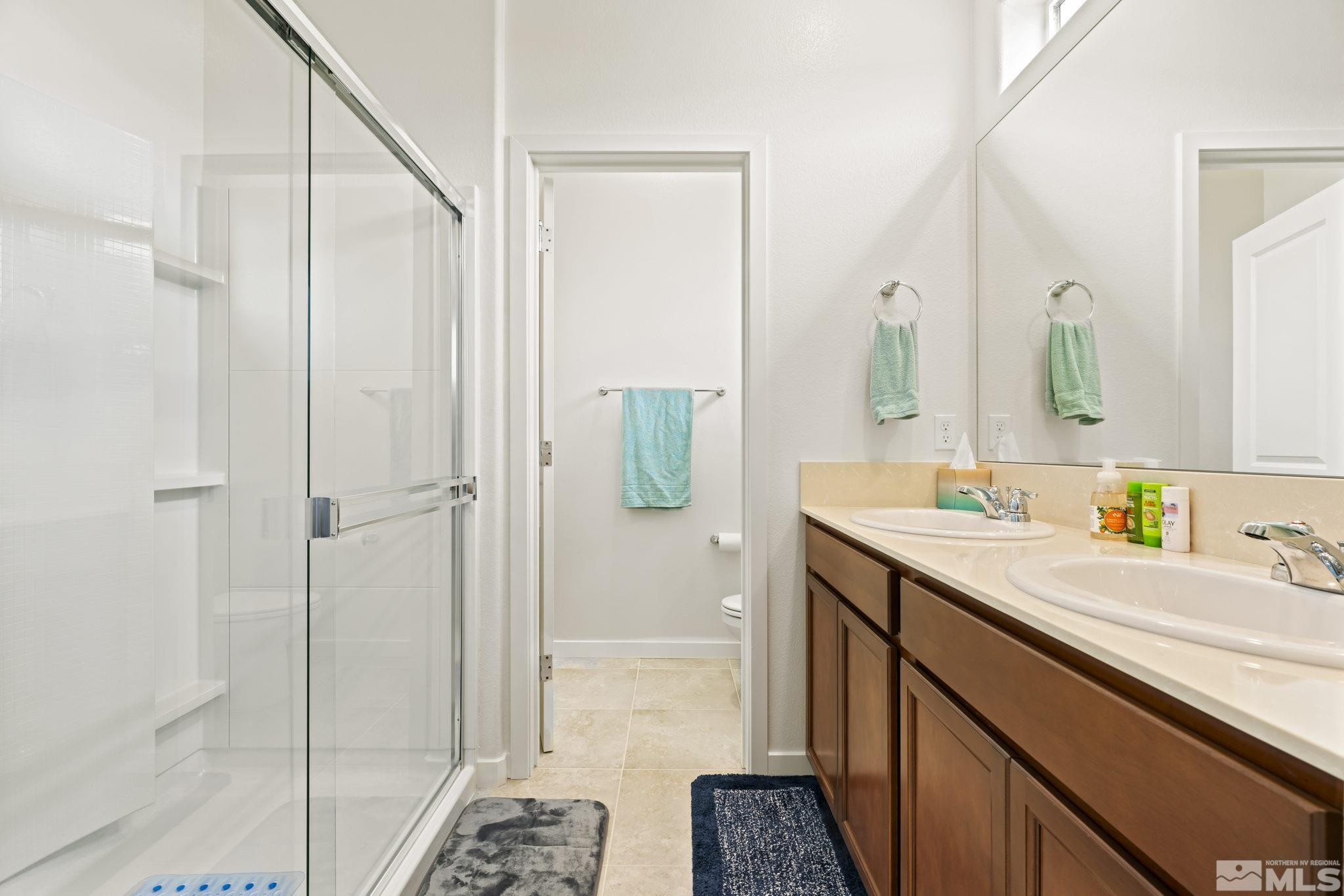 4920 Little Rock Way Sun Valley, NV 89433 - Photo 18 of 37 a bathroom with a sink a mirror and shower