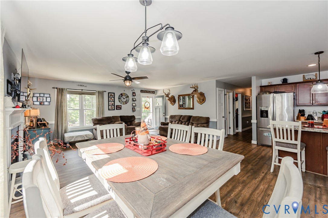 915 Manchester Road Bumpass, VA 23024 - Photo 12 of 49 a dining room with wooden floor a chandelier a wooden table and chairs