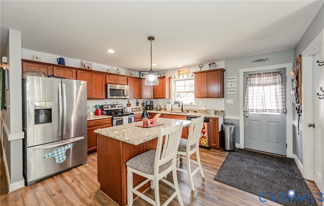 915 Manchester Road Bumpass, VA 23024 - Photo 16 of 49 a kitchen with stainless steel appliances a refrigerator a stove a sink dishwasher with a dining table and chairs