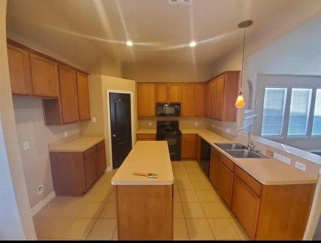 a large kitchen with stainless steel appliances kitchen island granite countertop a refrigerator and a stove top oven