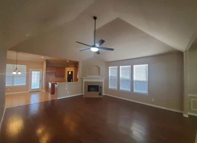a view of a livingroom with a fireplace a ceiling fan and wooden floor