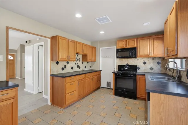 a kitchen with stainless steel appliances granite countertop a stove top oven a sink a refrigerator and white cabinets