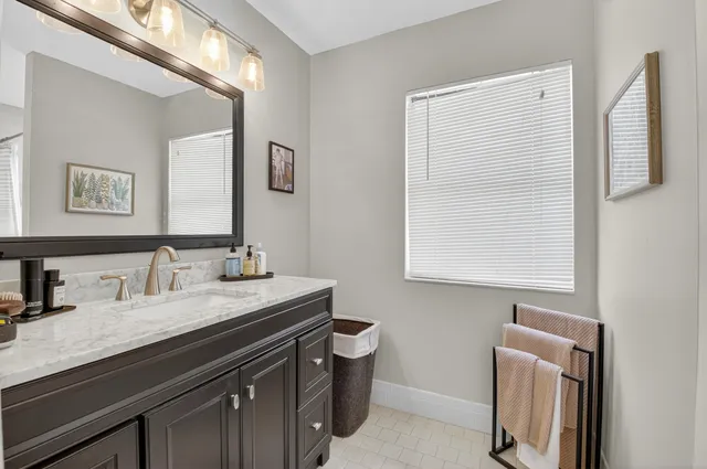 a bathroom with a granite countertop sink a toilet a mirror and a window