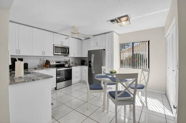 a kitchen with stainless steel appliances granite countertop a stove top oven a sink dishwasher a dining table and chairs with wooden floor