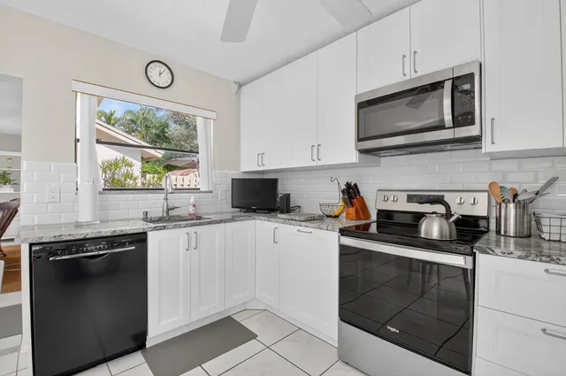 a kitchen with stainless steel appliances granite countertop white cabinets granite counter tops and a window