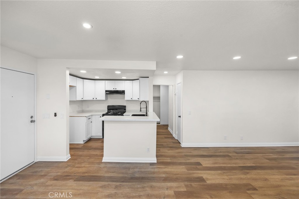 600 West 3rd Street, Unit B205 Santa Ana, CA 92701 - Photo 2 of 34 a large white kitchen with kitchen island a sink wooden floor and a refrigerator