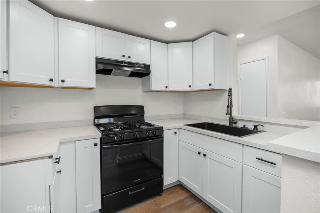 600 West 3rd Street, Unit B205 Santa Ana, CA 92701 - Photo 7 of 34 a kitchen with granite countertop white cabinets and a stove