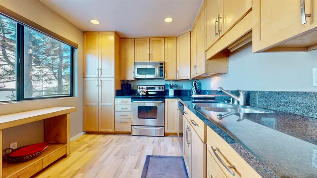 a kitchen with stainless steel appliances granite countertop dining table chairs refrigerator and sink