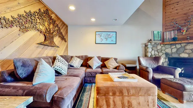 a living room with couches and kitchen view with wooden floor