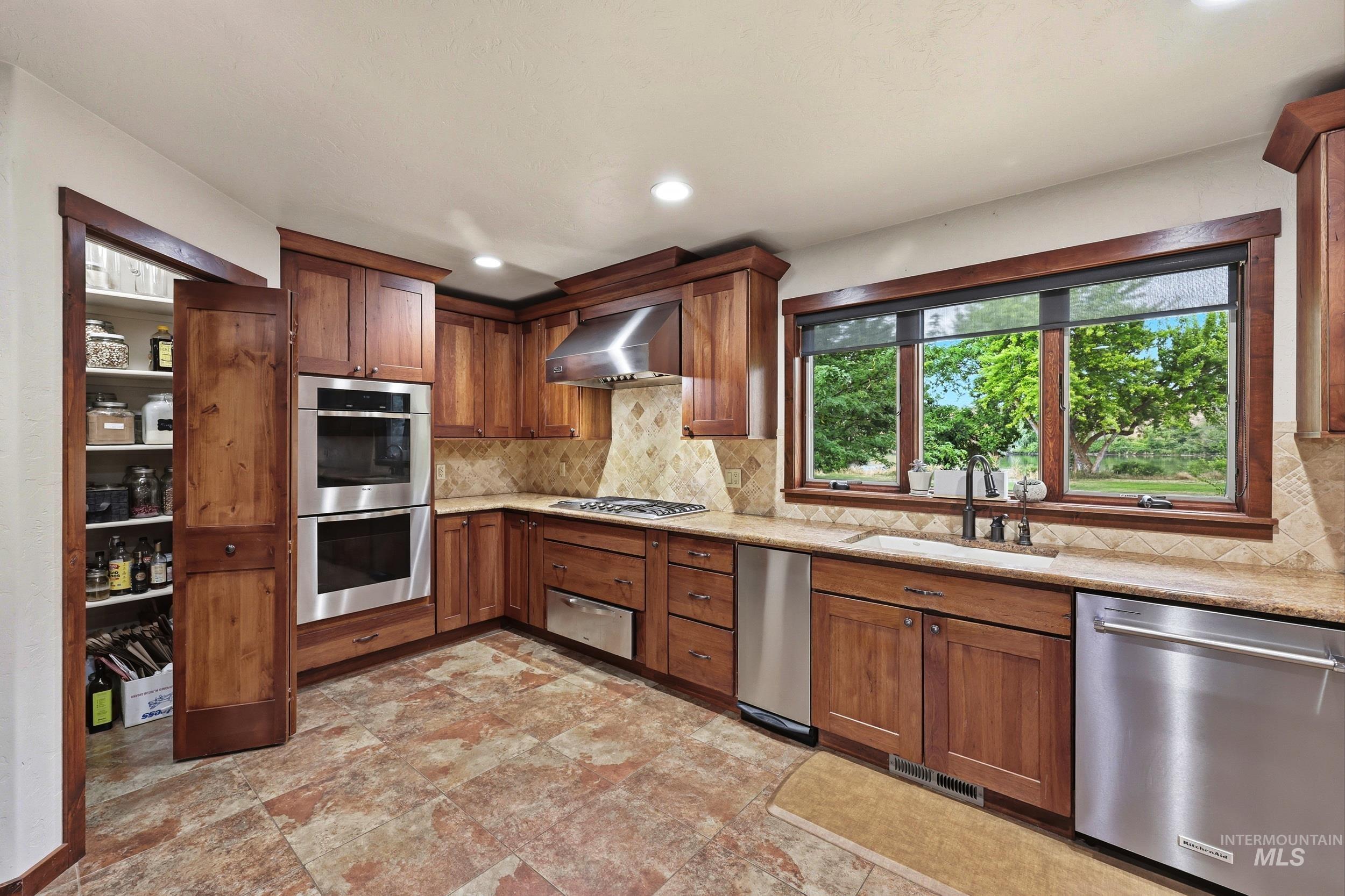339 Airport Road Weiser, ID 83672 - Photo 14 of 49 Kitchen featuring wood cabinetry, stainless steel appliances, natural stone countertops, a tile backsplash, and a window overlooking exterior greenery