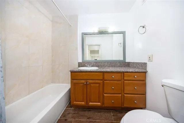 a bathroom with a granite countertop sink a mirror and a bathtub