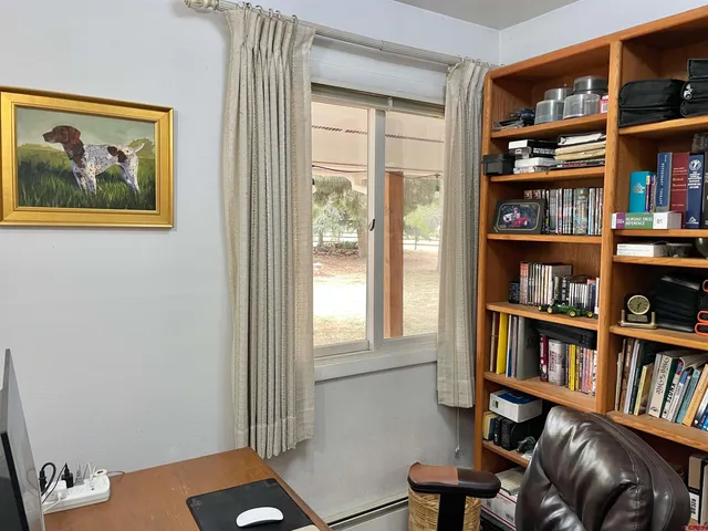 a view of a workspace with bookshelf and a window