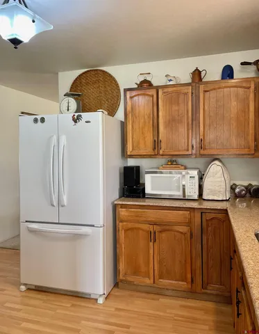 a kitchen with stainless steel appliances granite countertop a refrigerator a stove and a sink with wooden floors