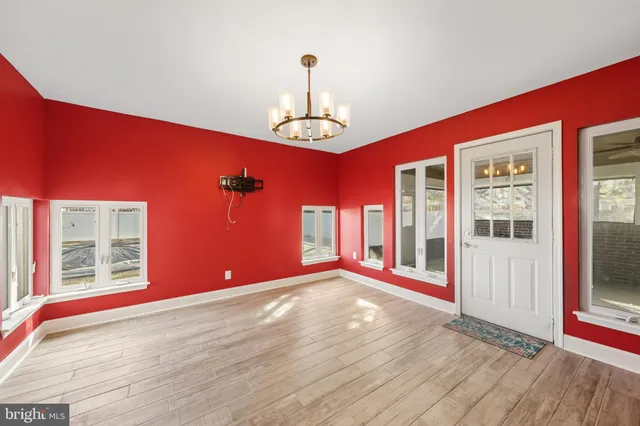 a view of an empty room with window and chandelier