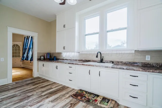an empty room with wooden floor fan and windows