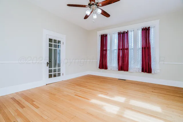 a view of a livingroom with a chandelier fan and wooden floor