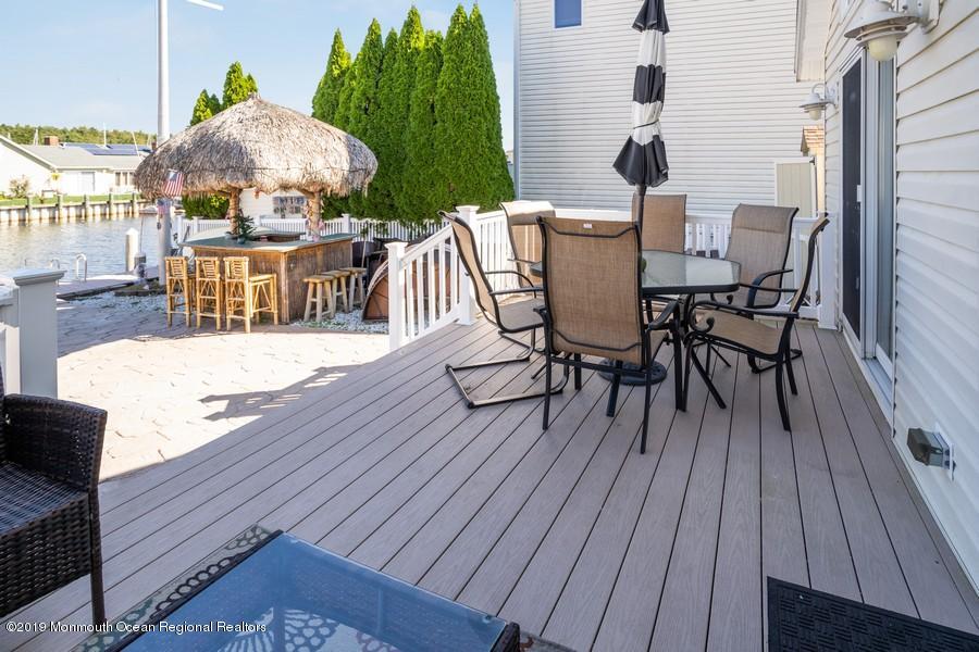 140 Cedar Run Road Bayville, NJ 08721 - Photo 14 of 18 a view of a roof deck with table and chairs a barbeque with wooden floor and fence