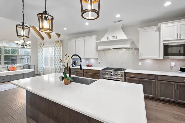 a kitchen with stainless steel appliances granite countertop a sink a stove and a wooden floors