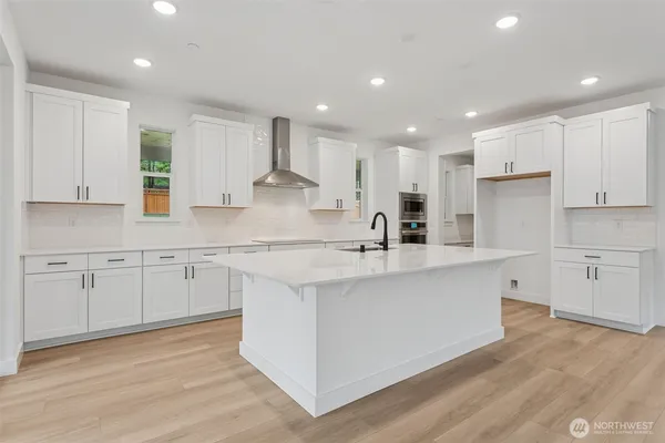 a kitchen with stainless steel appliances granite countertop a sink a stove a refrigerator and white cabinets