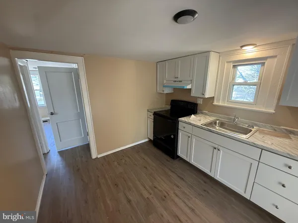 a kitchen with granite countertop a sink cabinets and wooden floor