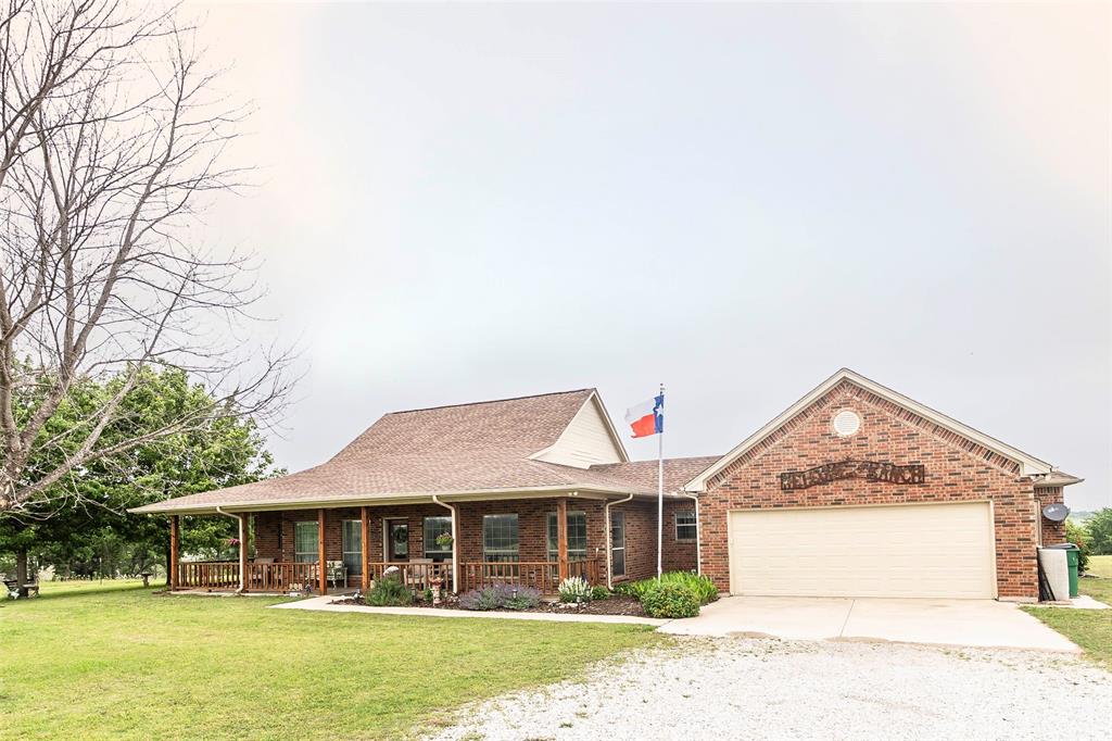 2168 Fruitland Road Sunset, TX 76270 - Photo 6 of 40 a view of a white house with a large windows and a yard with plants and large trees